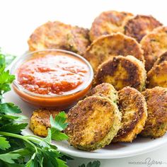 some fried food on a white plate with ketchup and parsley next to it