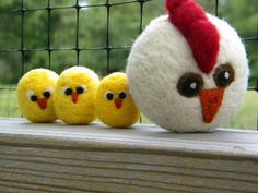 three small yellow chicks sitting next to a white egg on top of a wooden bench