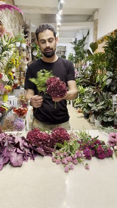 a man standing in front of a table filled with lots of flowers and greenery