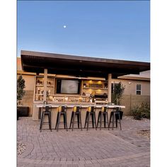 an outdoor bar with stools and a television