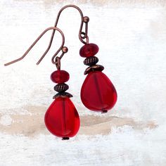 Cherry red glass teardrop earrings in copper. These exquisite Czech glass earrings are handcrafted using high-quality vintage beads and copper accents. The vibrant eye catching ruby red transparent beads add a nice pop of jewel color to enhance your look. Add a touch of Boho chic style to your look with these gorgeous cherry red beaded drop earrings. Elegant and eye-catching, these Boho teardrop earrings effortlessly elevate your style and are very versatile. They are perfect for any occassion a Vintage Red Copper Earrings, Vintage Copper Beaded Earrings For Gift, Copper Beaded Teardrop Earrings For Gifts, Vintage Red Beaded Earrings For Gift, Teardrop Copper Beaded Earrings For Gift, Vintage Red Beaded Earrings As Gift, Red Copper Earrings, Red Copper Drop Earrings, Handmade Red Teardrop Earrings