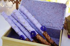 an open box filled with purple frosted doughnuts on top of a table