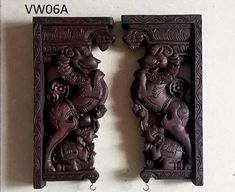 two carved wooden wall hangings with carvings on the top and bottom, one holding an elephant