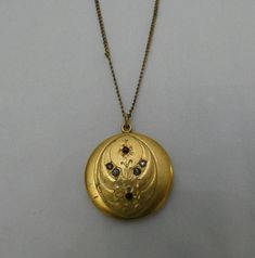 Antique Art Nouveau, Deco, gold tone locket pendent necklace. Locket has red and white jewels. Locket is marked R.B.M. Some wear due to age, missing one insert inside. Necklace has some knots, but otherwise in good condition. Locket 1.25" long, 1" wide, necklace 9.50" long. Victorian Locket Necklace For Ceremonial Occasions, Antique Gold Medallion Necklace For Gift, Antique Gold Necklace With Jewels, Traditional Gold Necklaces With Vintage Charm, Gold Locket Jewelry For Ceremonial Occasions, Gold Locket Necklace With 17 Jewels For Wedding, Traditional Gold Necklace With Vintage Charm, Gold Locket Jewelry For Ceremonial Use, Red Victorian Jewelry For Ceremonial Occasions