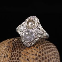 Beautiful Antique Art Deco Platinum Fancy Colored Diamond Filigree Two Stone Ring. This unbelievable band has two fancy colored diamonds in a pristine art deco mounting.Item #R0801Metal: PlatinumDiamonds: 1.17 ct Old Cut Fancy Grey and a 1.27 ct Old Cut Fancy Brownish Yellow. Clarity: VS2 - SI1Accent Diamonds: Approximately .50 ctsColor: HClarity: VS2Weight: 5.2 GramsRing Size: 5 1/2This ring can be sized for an additional $50Measurements: 17.9 mm widthMeasurement of the ring off the finger: 6.4 Antique Platinum Three Stone Diamond Ring, Art Deco Three Stone Platinum Jewelry, Art Deco Diamond Three Stone Ring, Art Deco Diamond White Diamond Ring, Art Deco Three Stone Diamond White Ring, Diamond White Three Stone Art Deco Ring, White Brilliant Cut Filigree Ring In Art Deco Style, Art Deco White Filigree Ring With Brilliant Cut, Vintage White Three Stone Diamond Ring