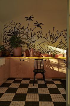 a kitchen with black and white tile flooring next to a wall painted with palm trees