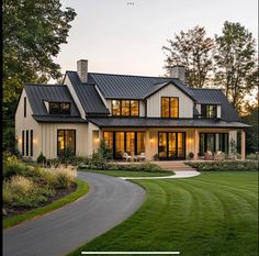 a large white house with lots of windows and grass in front of the house is surrounded by trees