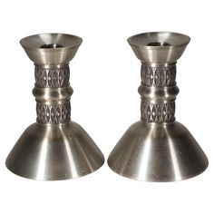 two metal candlesticks sitting next to each other