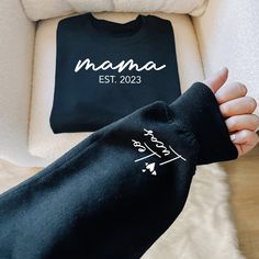 "Custom Mama Sweatshirt with Date and Childs Name on Sleeve, New Mom, Personalized Mom Hoodie, Minimalist Mom Sweater, Birthday Gift for Mom ----------- How to Order Your Custom Design T-shirt ---------- * Choose your t-shirt color * Choose your size * PLEASE make sure all your order's steps Please type: Only name(s) on the sleeve (For multiple names, please list commas between them) And please type Est. Year -The text on the chest and the hearts on the sleeve will be automatically added -Names are printed on one sleeve only For Example: Leo, Lucas Est. 2023 ---------- Product ---------- * 4.2 oz., 100% airlume combed and ringspun cotton, 32 singles * 32 singles Athletic Heather and Black Heather are 90/10 airlume combed and ringspun cotton/polyester Ash is 99/1 airlume combed and ringspun Mother's Day Sweatshirt With Custom Text, Black Hooded Sweatshirt Gift, Black Hooded Sweatshirt As Gift, Black Long Sleeve Sweatshirt With Name Print, Black Long Sleeve Sweatshirt With Custom Text, Mother's Day Black Crew Neck Sweatshirt, Casual Black Sweatshirt For Birthday, Black Casual Sweatshirt, Custom Text Long Sleeve Sweatshirt For Winter