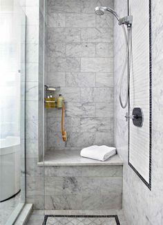 a walk in shower sitting next to a tiled wall