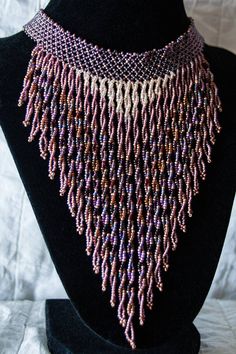 a purple and white beaded necklace on a black mannequin