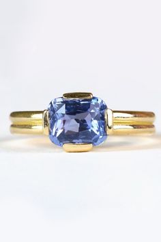 The serene blue of Sri Lankan origin sapphire is world known for its rarity and beauty. This stunning and glowing blue sapphire is natural and untreated in any way. Set minimally in a low profile double band 18k recycled yellow solitaire. Gold Sapphire Ring With Cushion Cut, Gold Cushion Cut Sapphire Ring, Modern Blue Sapphire Ring, Timeless Blue Sapphire Ring, Yellow Gold Sapphire Ring With Cushion Cut, Cushion Cut Sapphire Ring In Yellow Gold, Classic Blue Asscher Cut Sapphire Ring, Minimalist Blue Round Cut Sapphire Ring, Classic Ethical Sapphire Ring