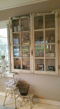 an old china cabinet with glass doors on the wall and two stools in front of it