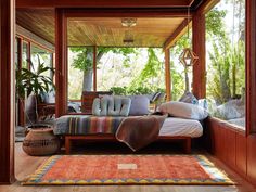 a bed sitting on top of a wooden floor next to a lush green tree filled forest