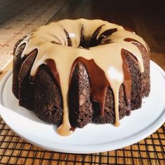 a chocolate bundt cake with icing and drizzled on top sitting on a white plate