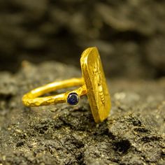 a gold ring sitting on top of a rock with a blue stone in the middle