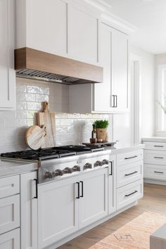 a kitchen with white cabinets and wooden cutting boards on the stove top, along with potted plants