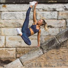 a woman in blue sports bra and leggings doing a handstand on some steps