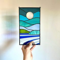 a hand holding up a stained glass panel