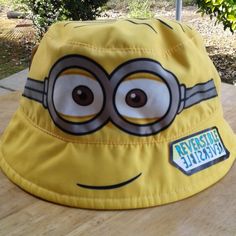 a yellow bucket hat with a cartoon character on the front and side, sitting on top of a wooden table