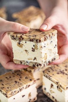 someone is holding some kind of dessert with chocolate chips on top and white frosting