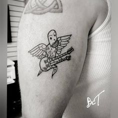 a person with a tattoo on their arm holding a guitar and an angel above his head