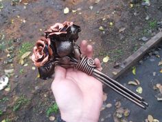 a person holding an object in their hand with metal rods and flowers on top of it