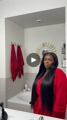 a woman standing in front of a bathroom mirror next to a sink and bathtub