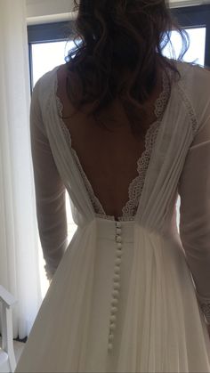 the back of a woman's wedding dress in front of a window