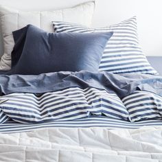 a bed topped with blue and white pillows next to a pillow on top of it