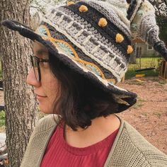 a woman wearing a knitted hat in front of a tree