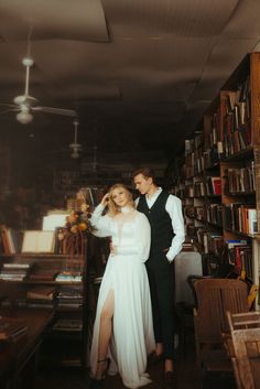 a man and woman standing next to each other in front of a bookshelf