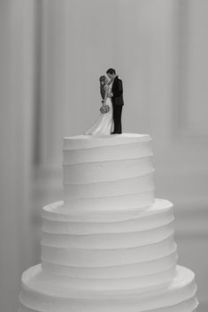 a black and white photo of a bride and groom on top of a wedding cake