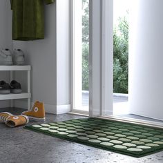 a pair of shoes sitting on the floor next to a green rug in front of an open door