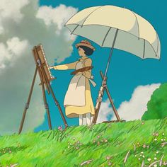 a woman standing on top of a lush green field holding an umbrella next to easels