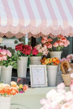 flowers are on display at an outdoor flower shop with pink and white striped awning