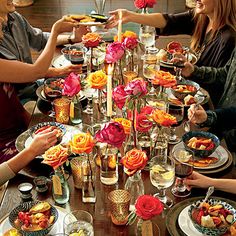 a magazine with people sitting at a table eating food and drinking wine, surrounded by flowers