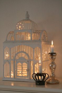 a white birdcage with lit candles in front of it