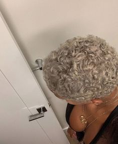 a woman with grey hair standing in front of a door