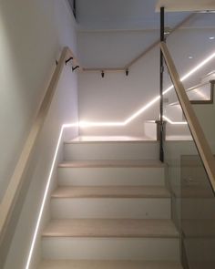 some stairs with lights on them in a room that is white and has wooden handrails