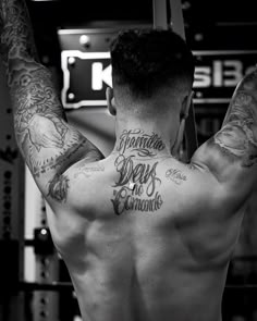 a man with tattoos on his back in the gym