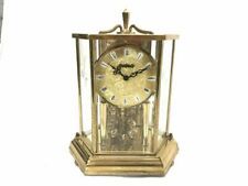 an antique brass clock with roman numerals on the face and hands, sitting against a white background