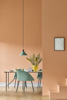 a dining room with pink walls and blue chairs