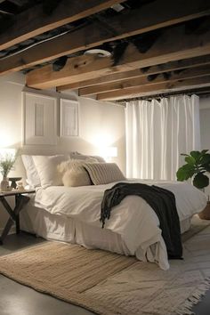 a white bed sitting under a wooden beam in a bedroom next to a table with a lamp on it