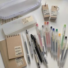 several pens and markers are laid out on a table next to some envelopes with tags