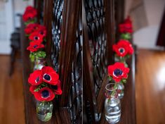 two vases filled with red flowers sitting on top of a wooden table next to each other