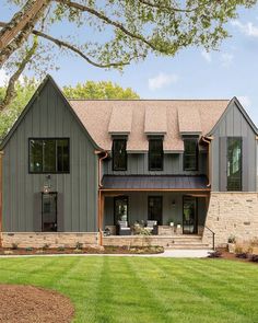 a large gray house sitting on top of a lush green field