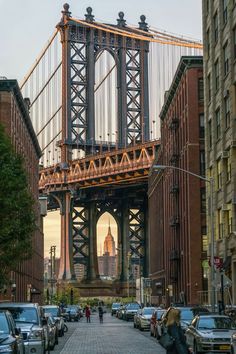 cars are parked on the street in front of tall buildings with a bridge above them