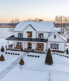 a large white house with lots of windows and trees in the front yard covered in snow