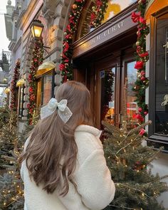 a woman standing in front of a store with christmas decorations on the windows and doors